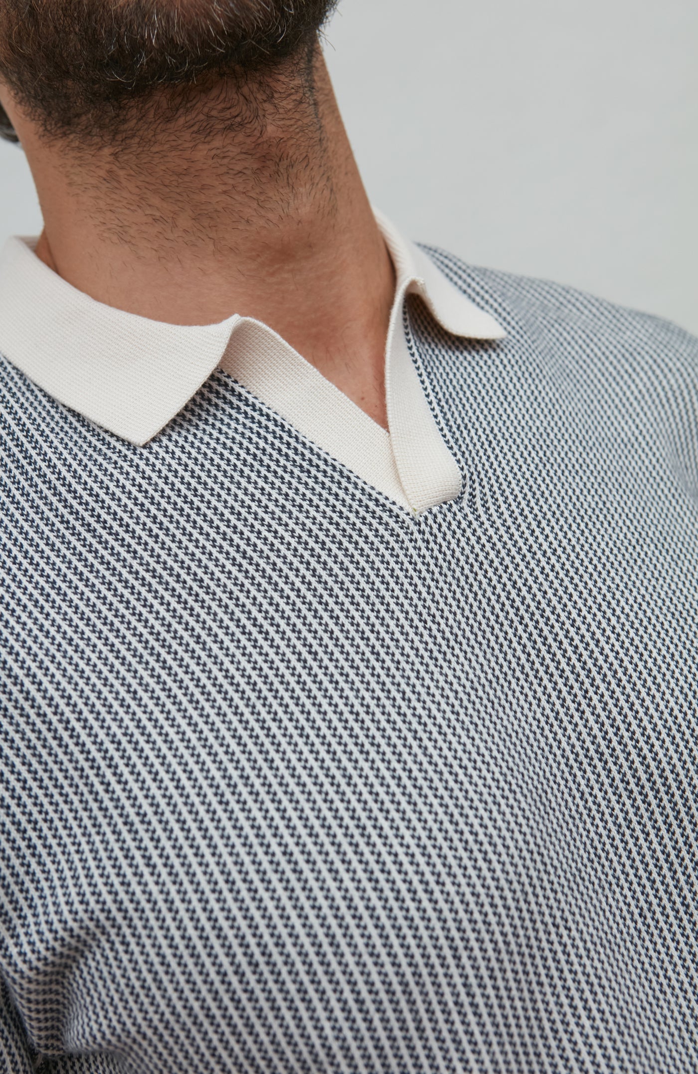 buttonless polo Close-up of a person wearing a patterned shirt with a white collar.