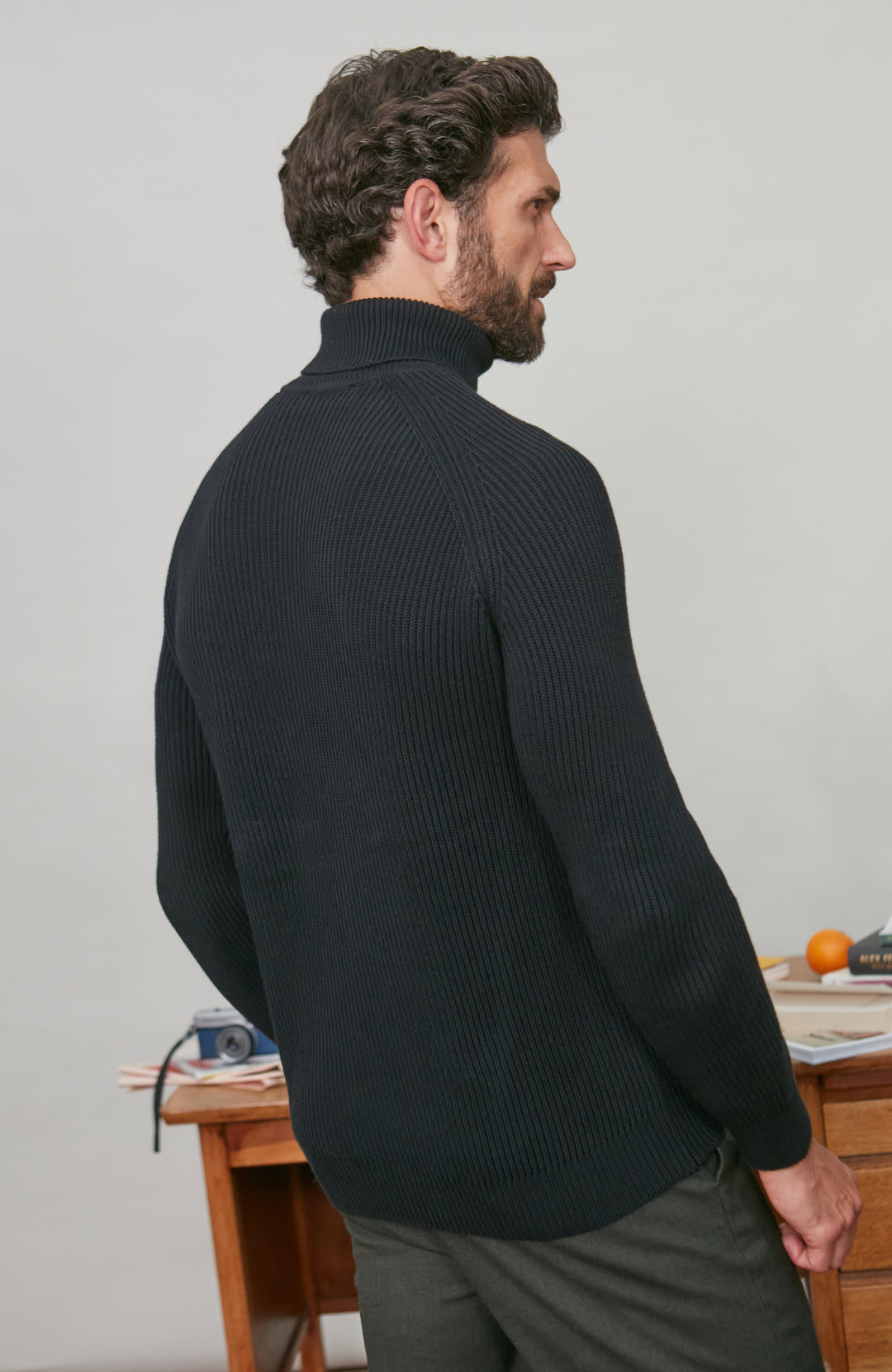 Man wearing a black cotton turtleneck sweater against a plain background