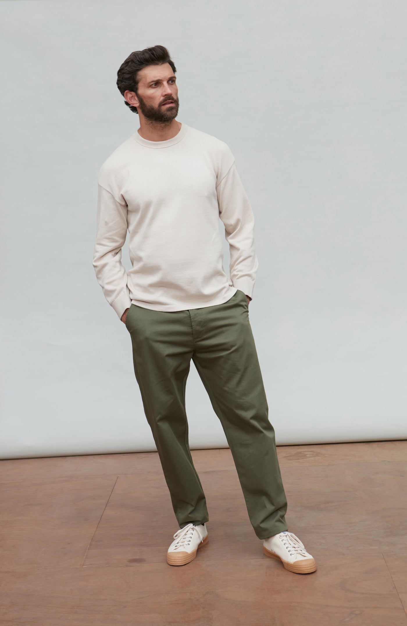 Man wearing a white cotton sweater against a plain background