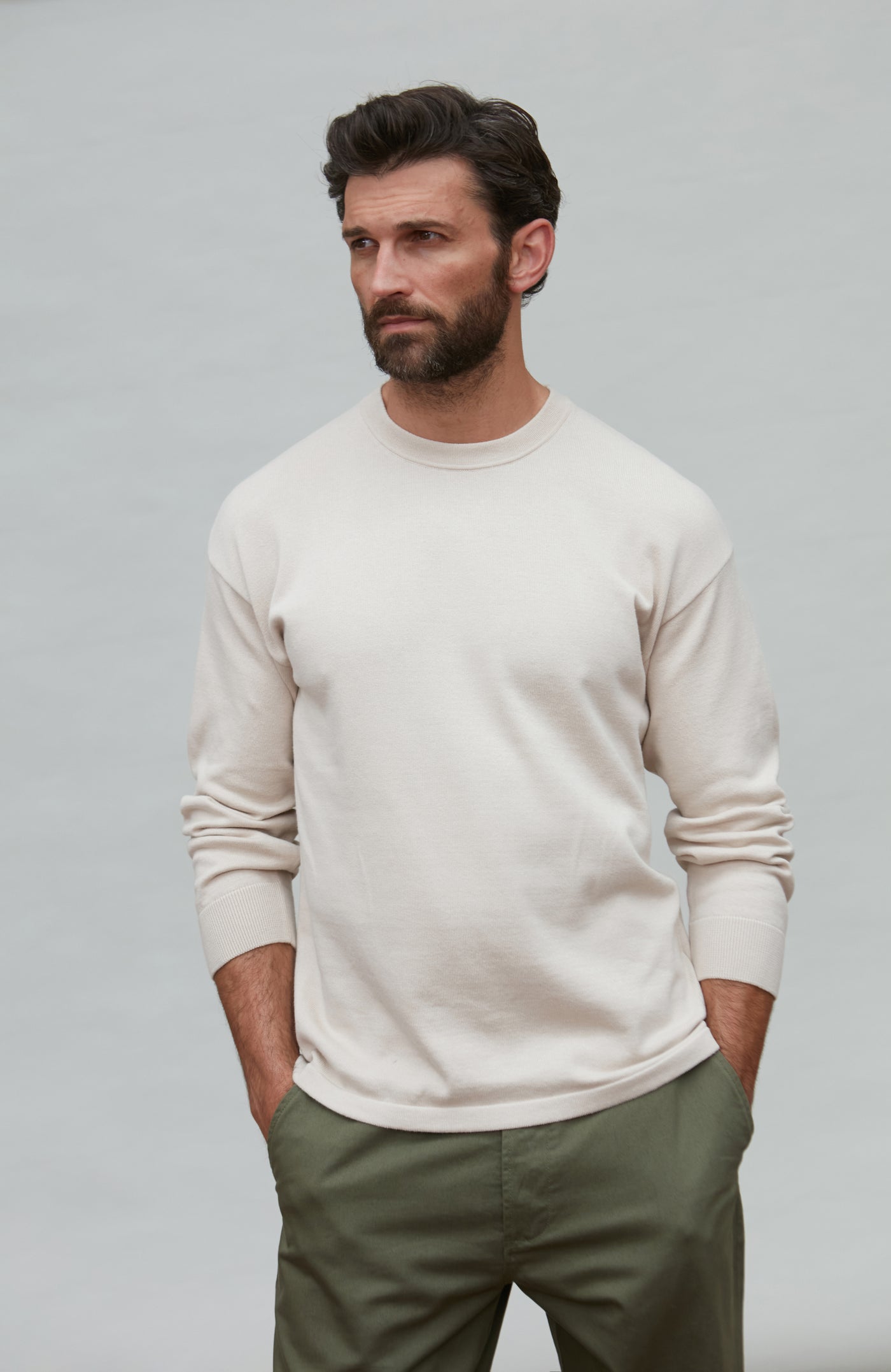 Man wearing a white cotton sweater against a plain background