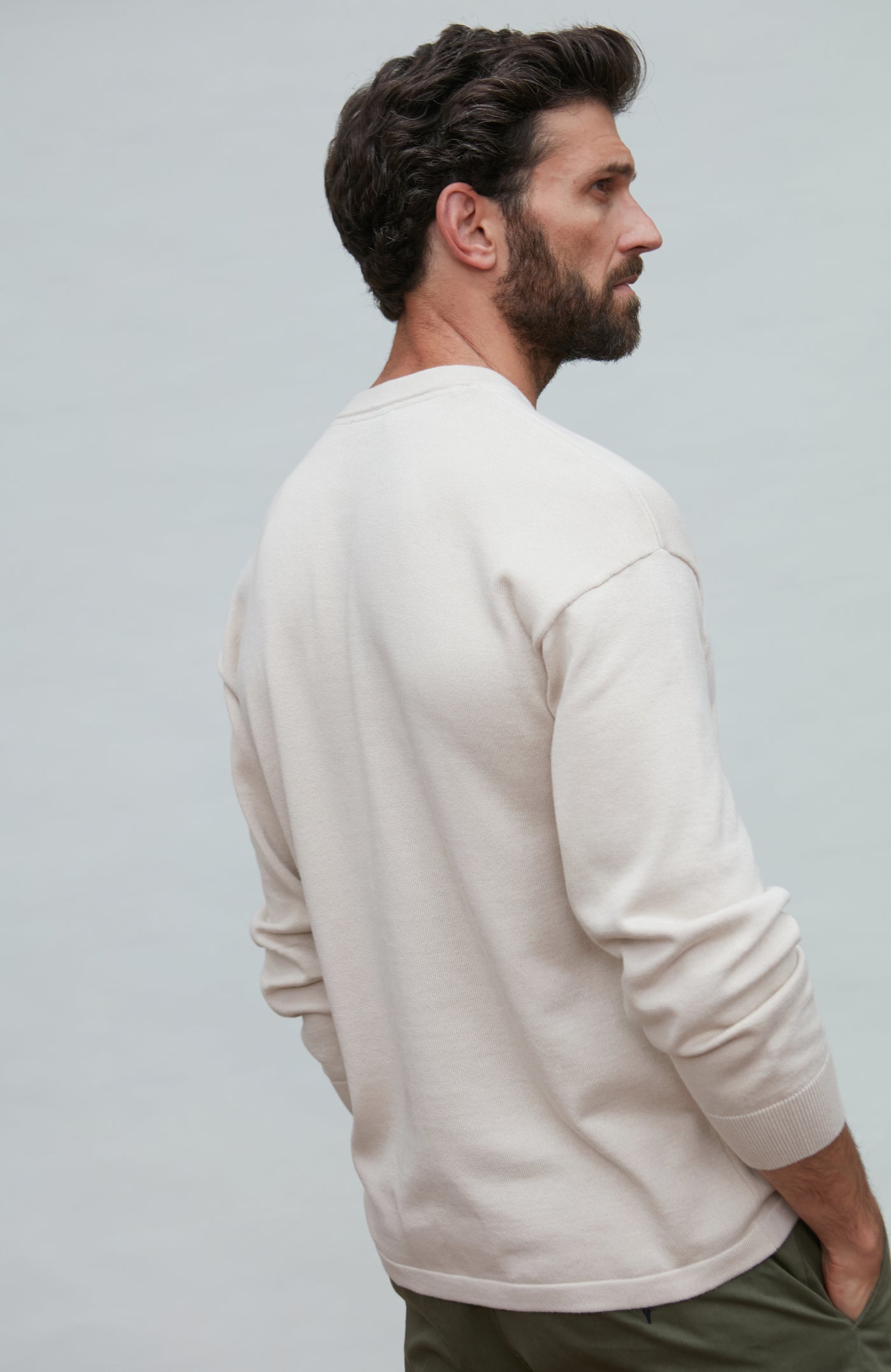 Man wearing a white cotton sweater against a plain background