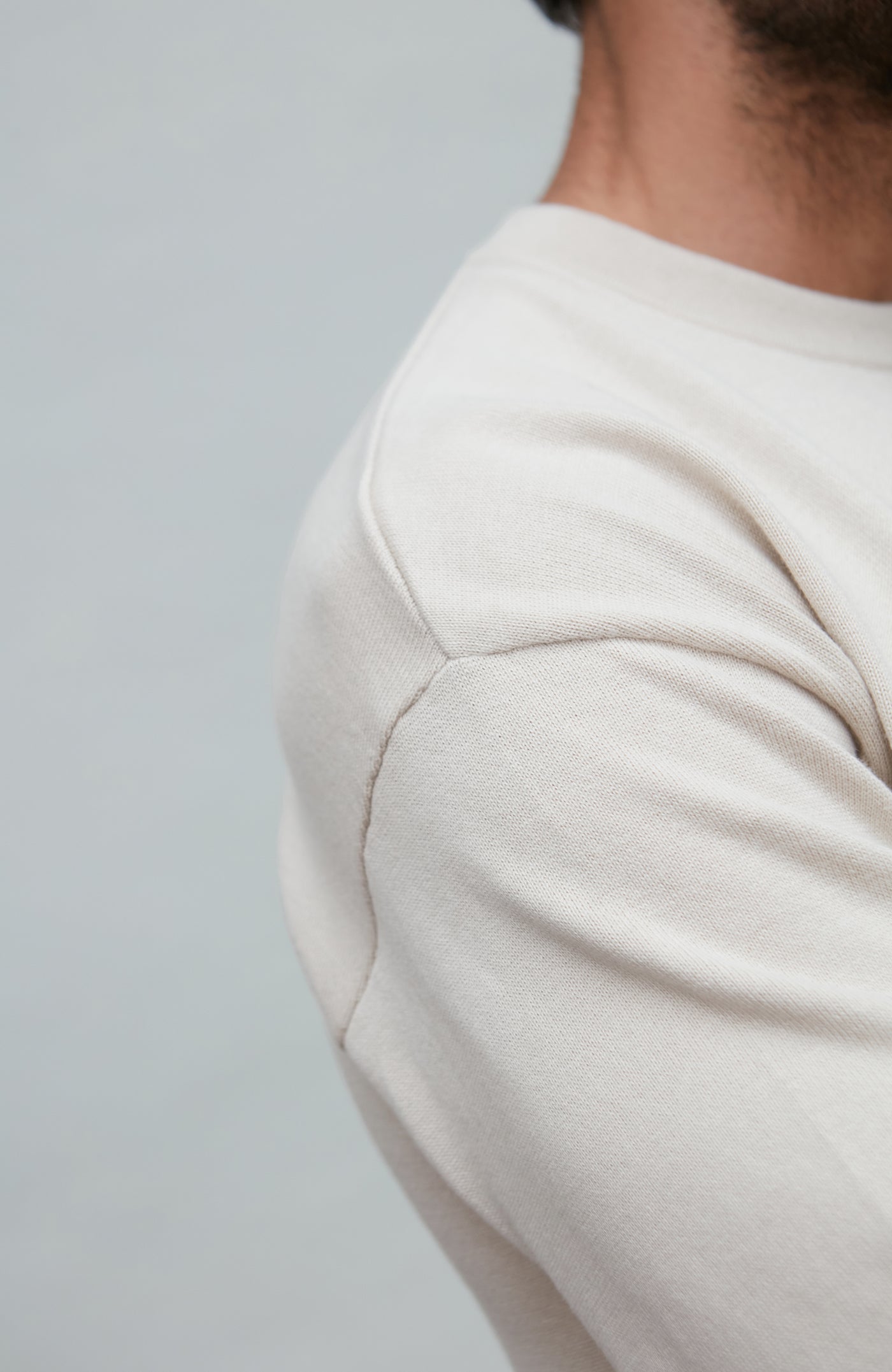 Man wearing a white cotton sweater against a plain background