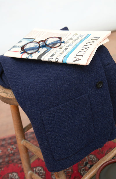 Man wearing a blue wool blazer over a white shirt with a light gray background