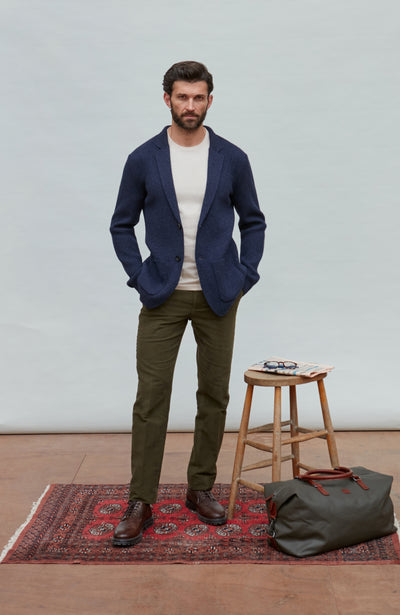 Man wearing a blue wool blazer over a white shirt with a light gray background