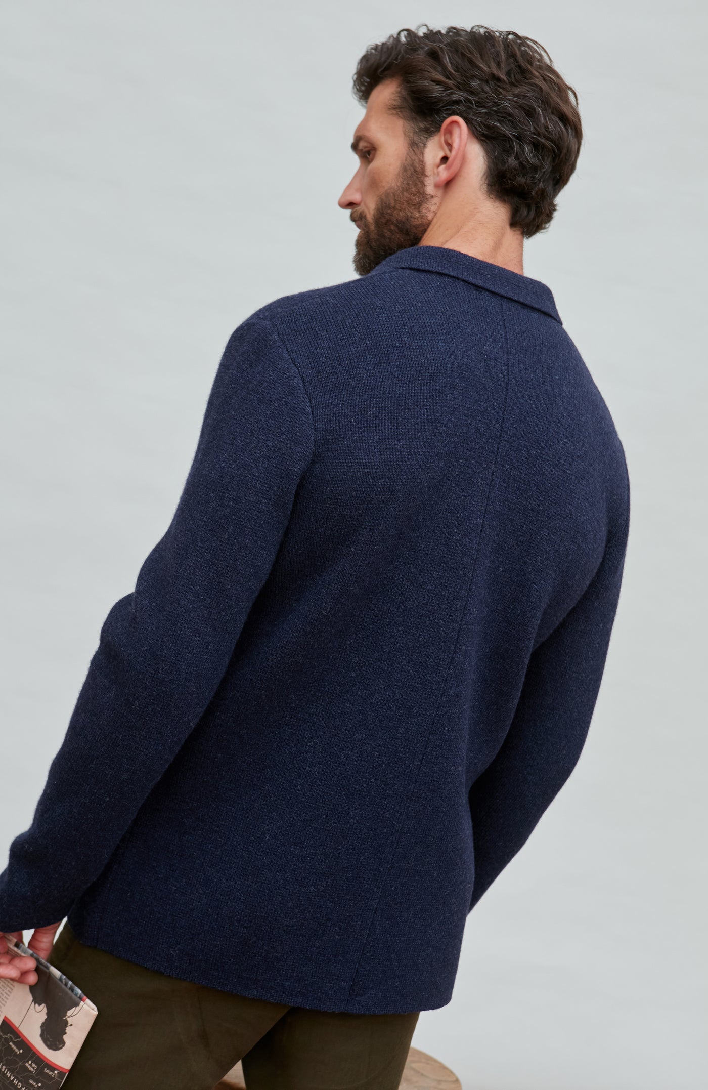 Man wearing a blue wool blazer over a white shirt with a light gray background