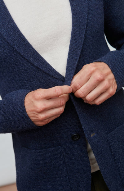 Man wearing a blue wool blazer over a white shirt with a light gray background