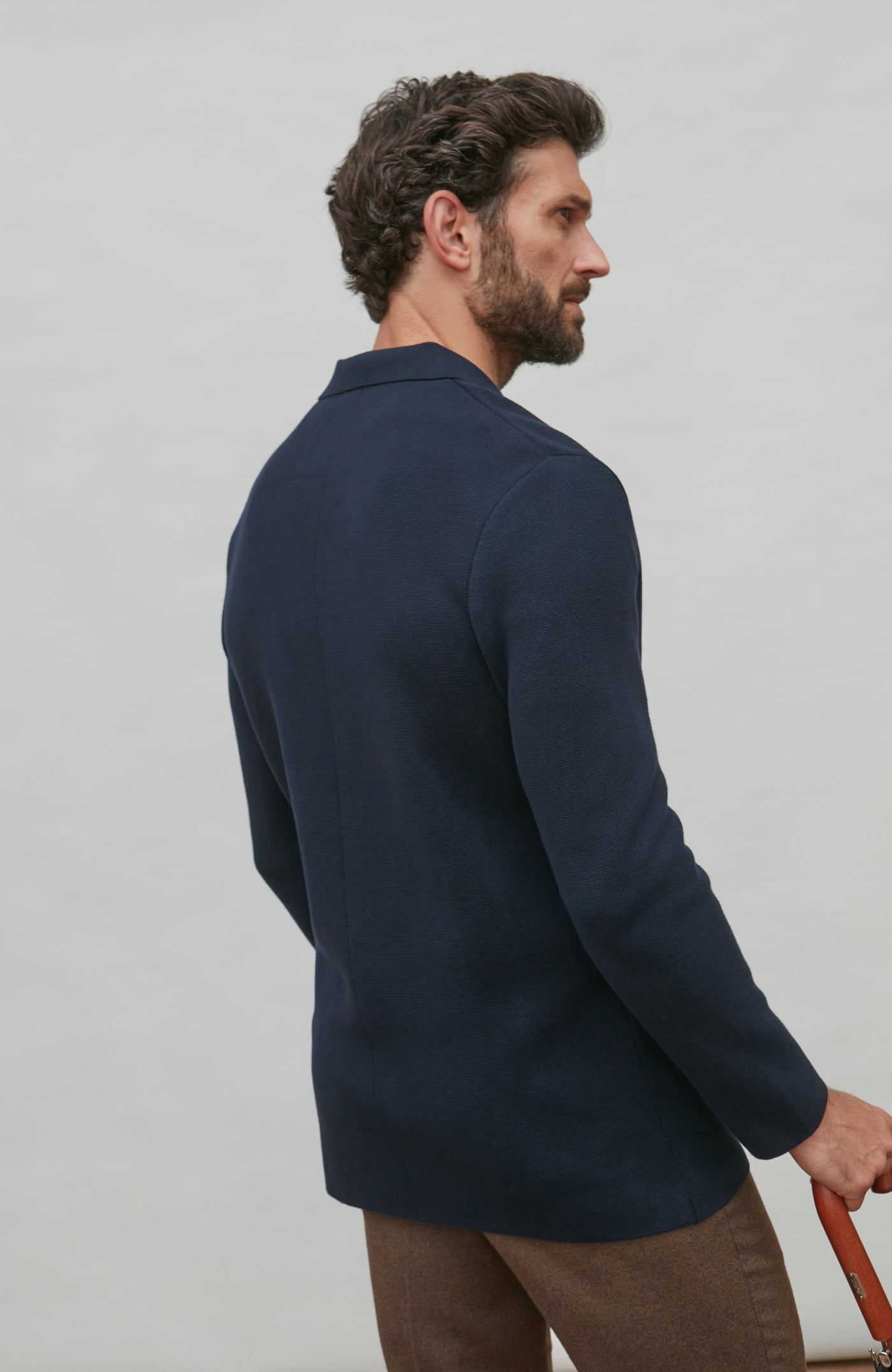 Man wearing a navy double breasted blazer against a light gray background