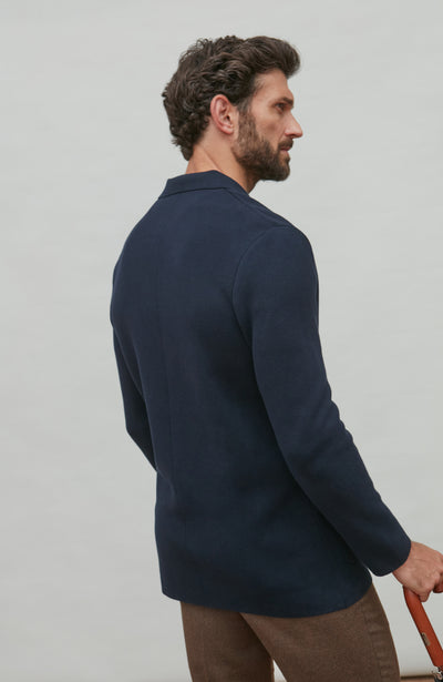 Man wearing a navy double breasted blazer against a light gray background