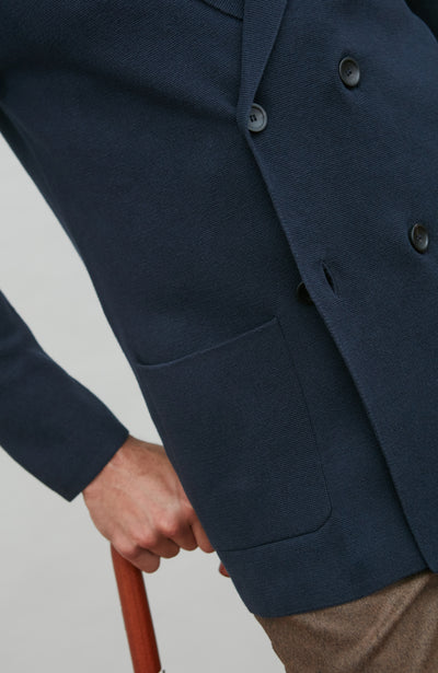 Navy blue double breasted blazer with a pocket and buttons on a light gray background