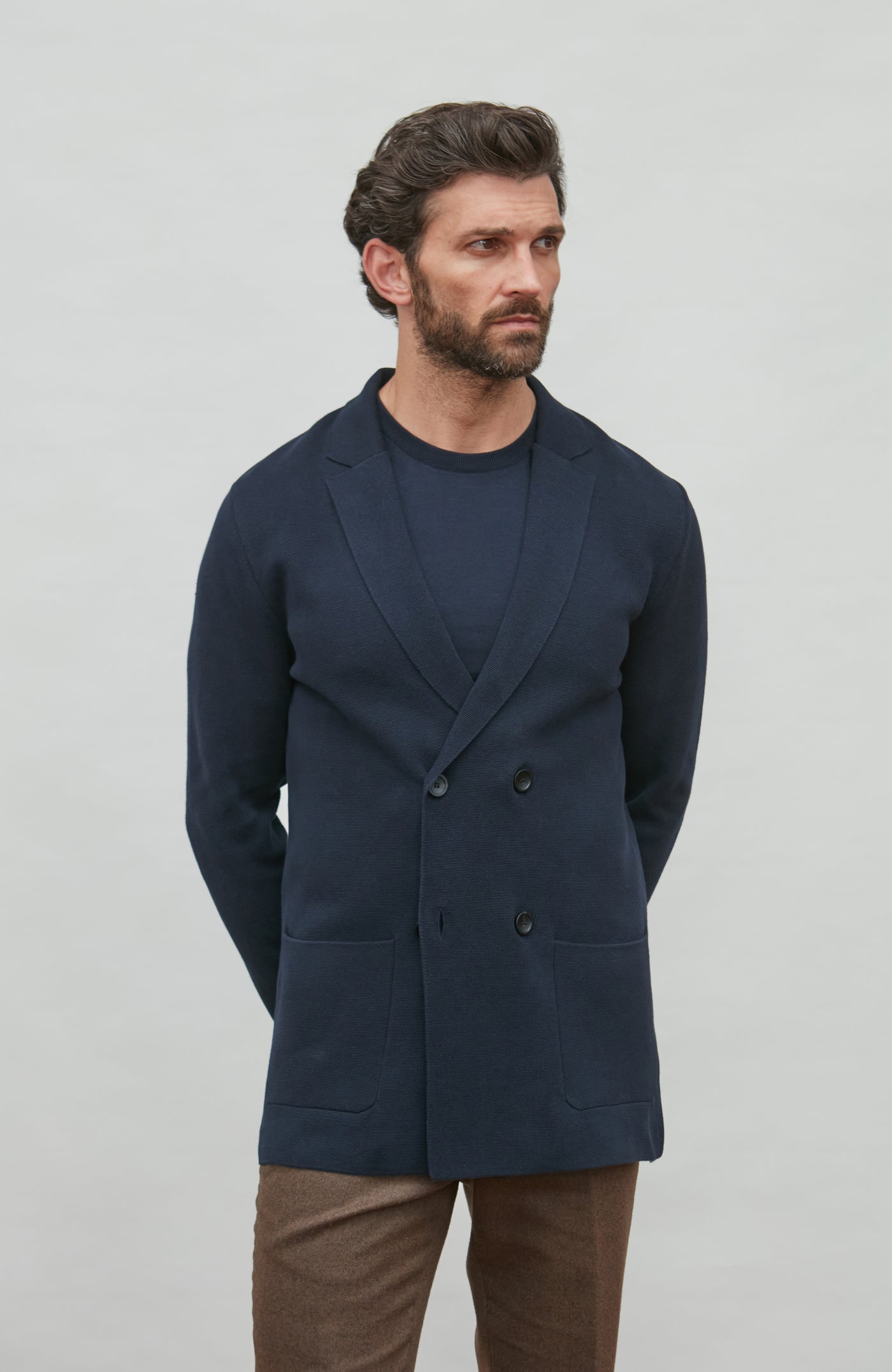 Man wearing a navy blue double breasted blazer against a plain background