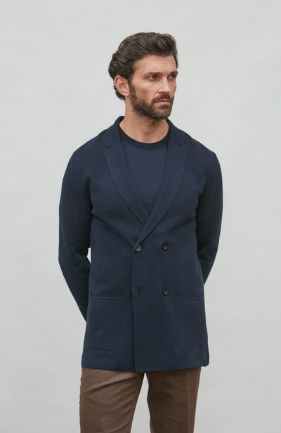 Man wearing a navy blue double breasted blazer against a plain background