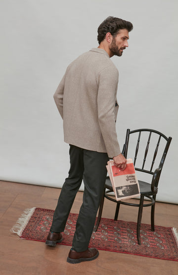 Man holding a newspaper, standing in a room with a chair and rug.