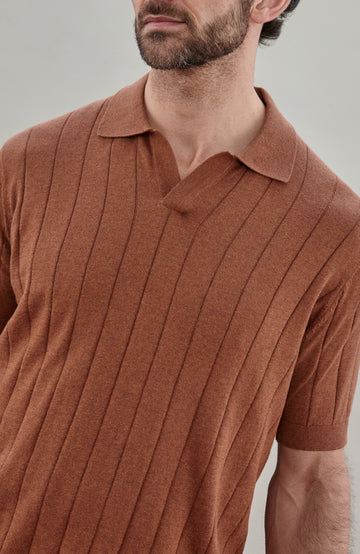 Man wearing a brown cotton ribbed polo shirt by Paul James Knitwear against a plain background