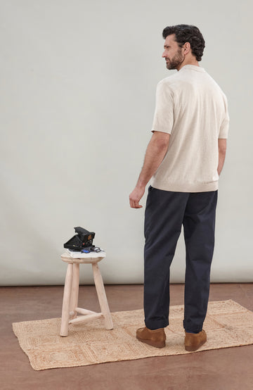 A man in wearing a light beige cotton knit short-sleeve polo shirt by Paul James Knitwear