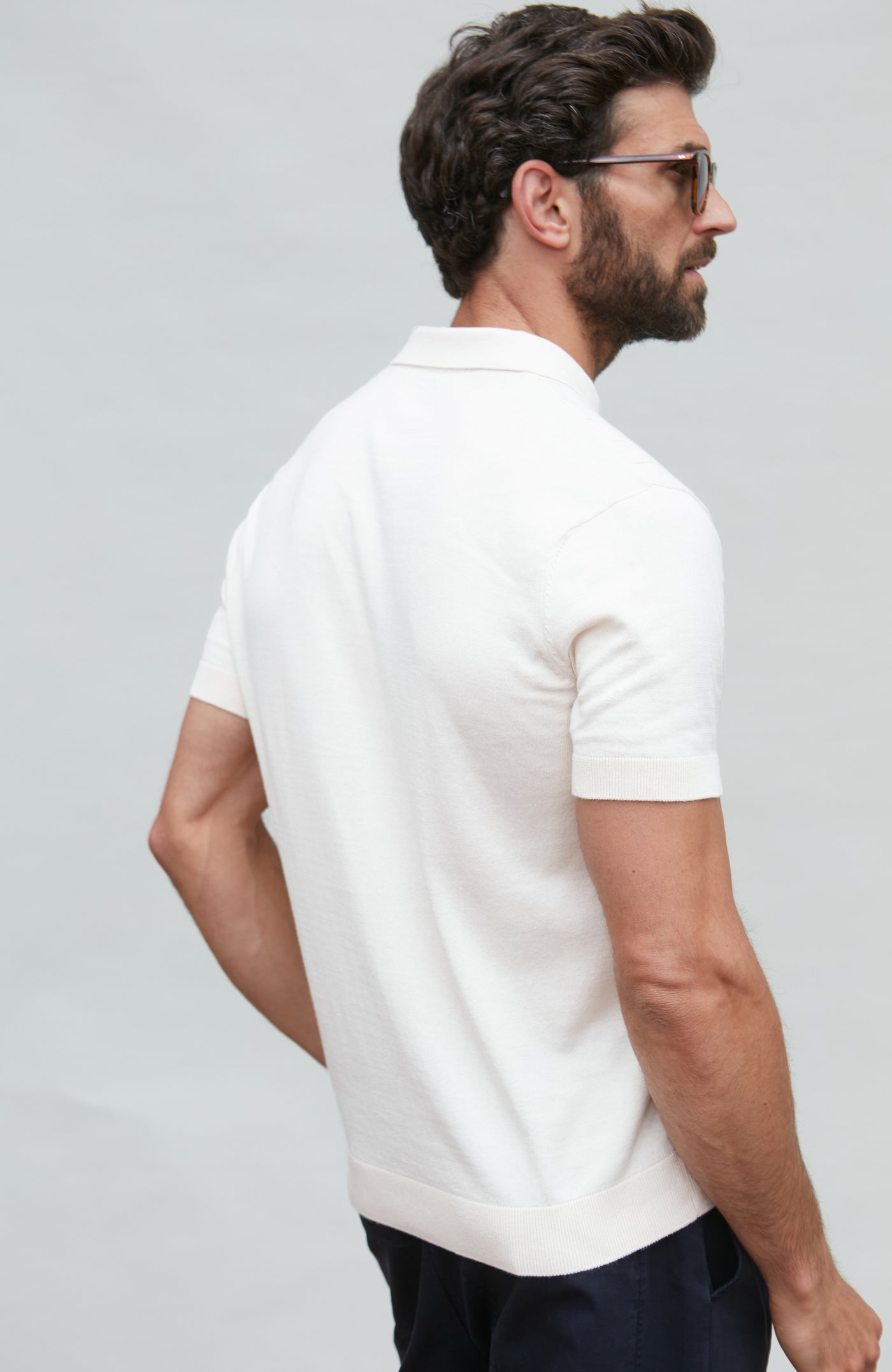 Man wearing a white polo shirt on a light gray background