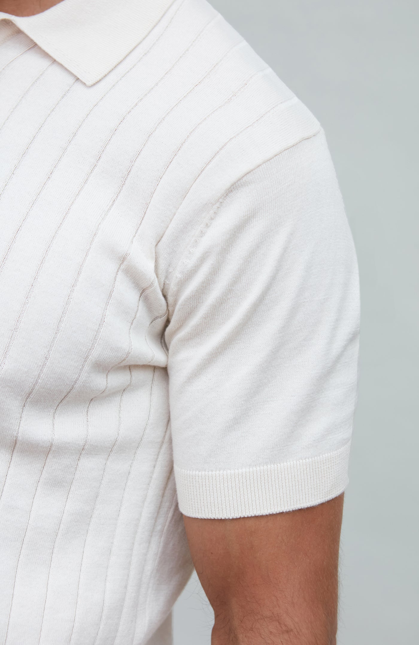 Close-up of a person wearing a white short-sleeve shirt against a gray background