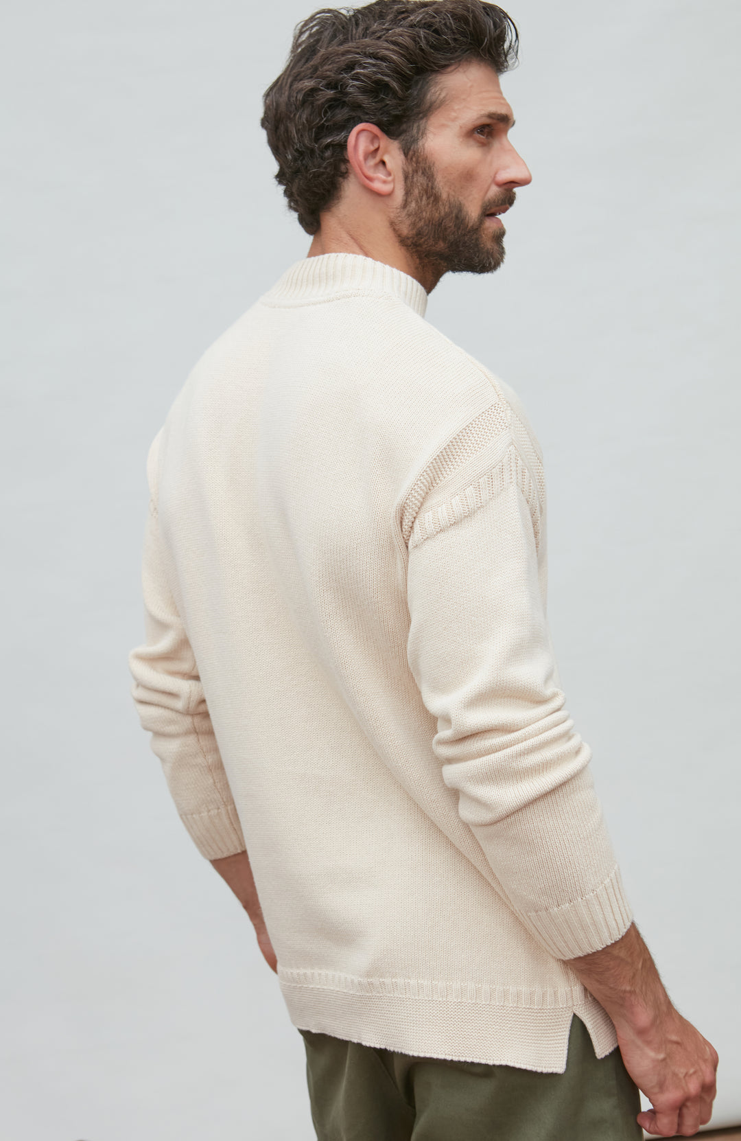 Man wearing a cream guernsey sweater against a light gray background