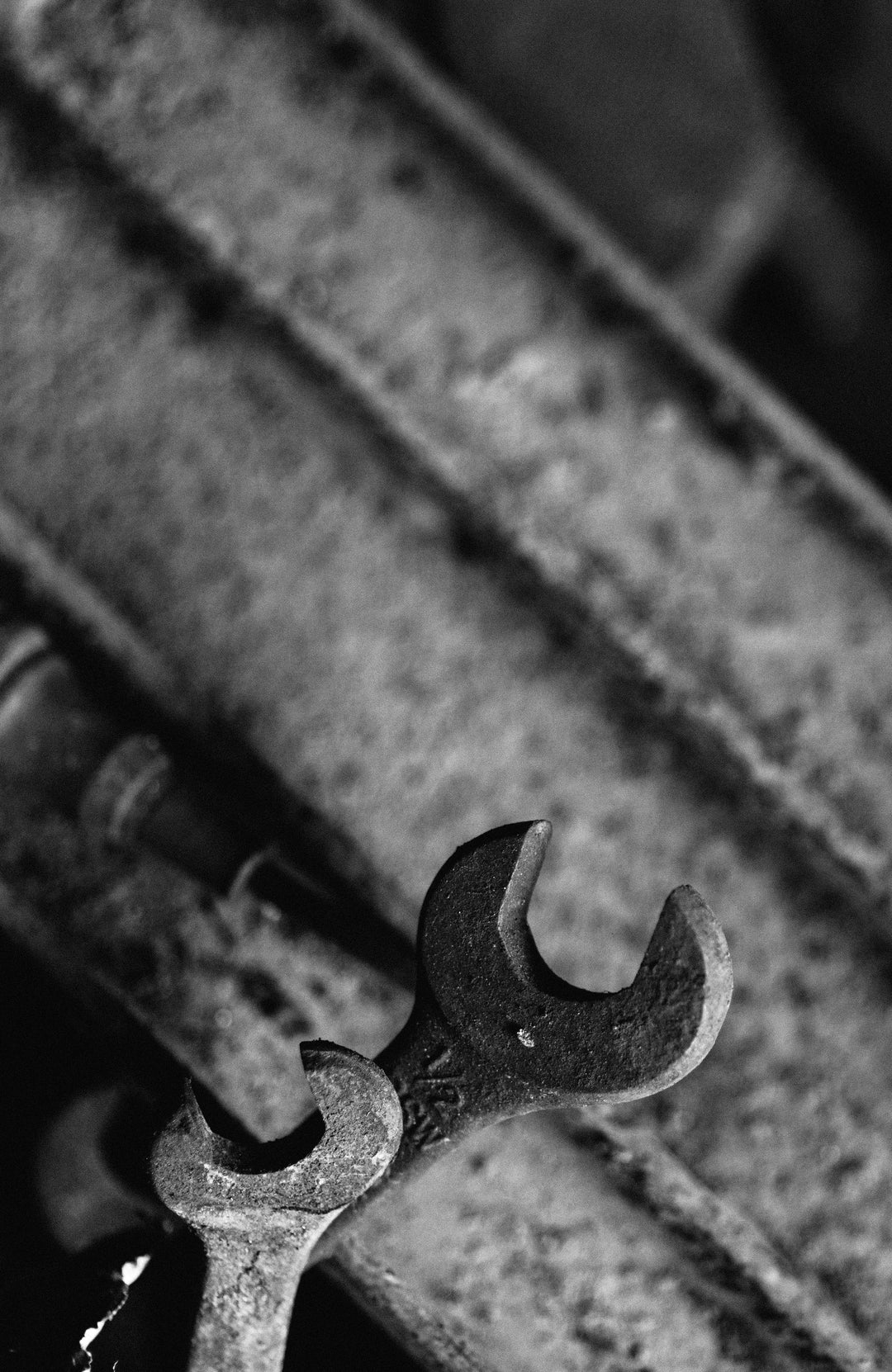 Close-up of a rusty wrench on a textured metal surface