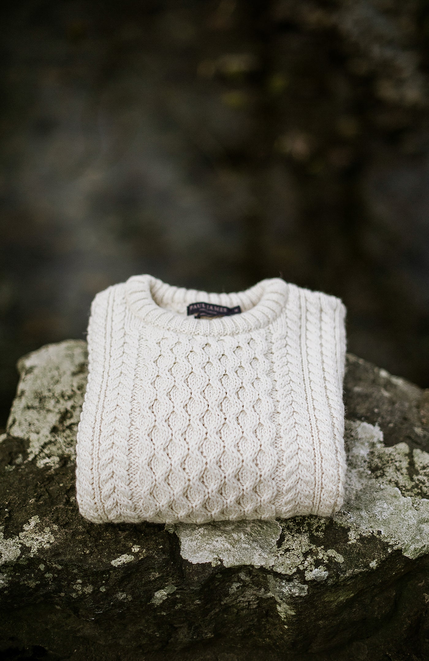 Knitted cable sweater on a stone surface with a blurred natural background