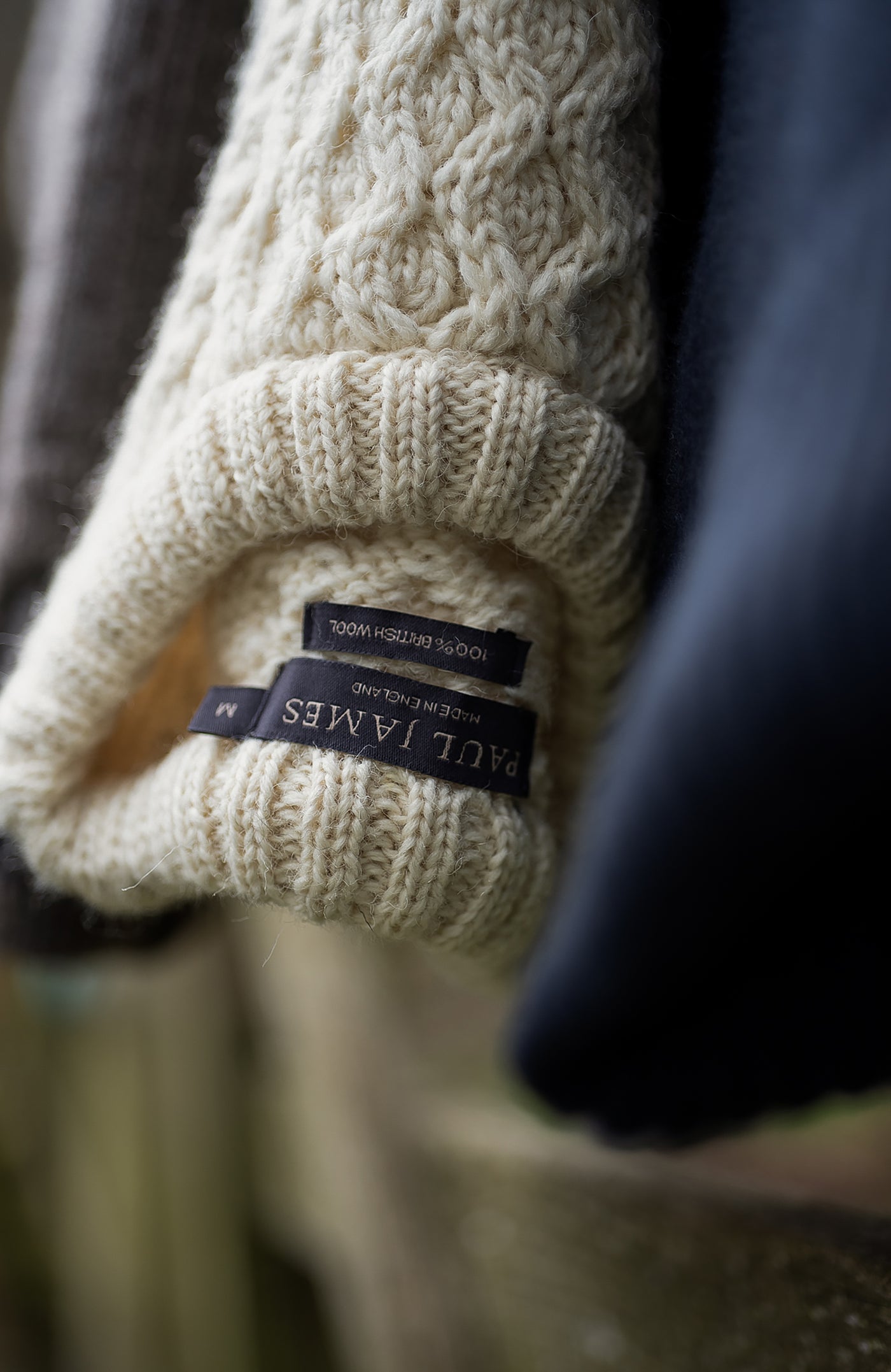 Close-up of a beige knitted wool knitted sweater with a label on a blurred background