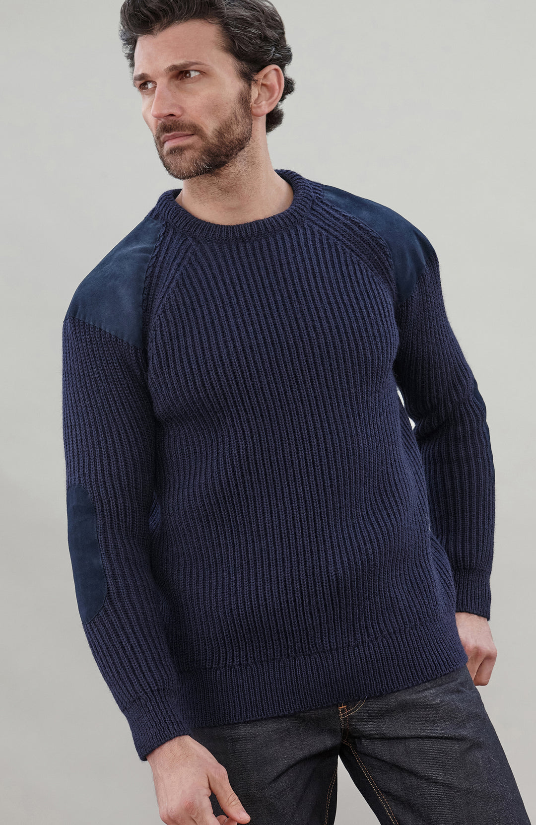 Man wearing a navy blue British wool made in England ribbed shooting sweater against a plain background