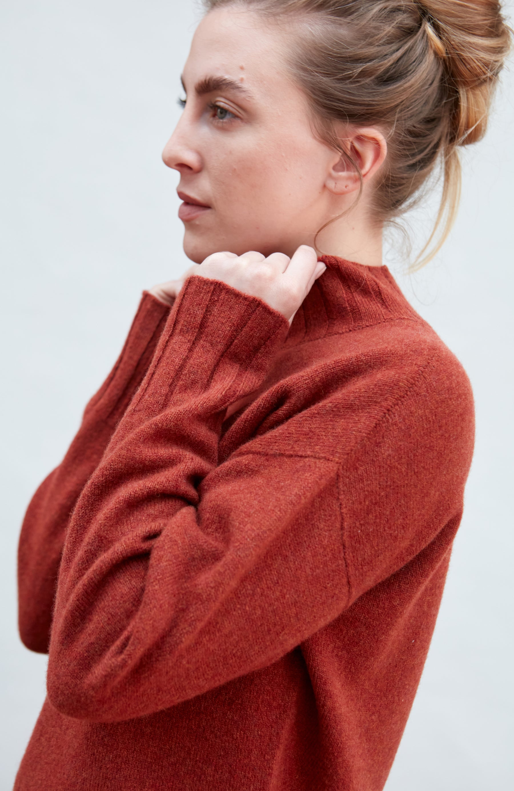 Woman wearing a red wool turtle neck sweater against a light background