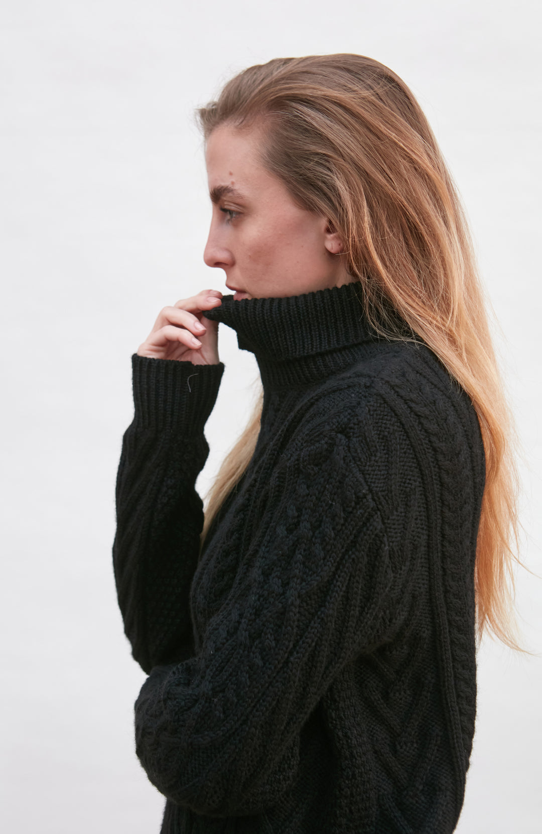 Woman wearing a black cable knit sweater by paul james knitwear