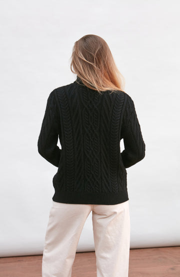 Woman wearing a black cable knit wool sweater by paul james knitwear