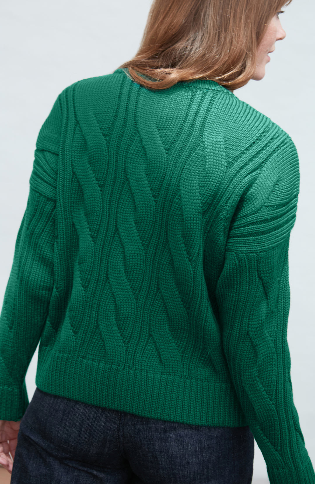 Green cable paul james wool knit sweater worn by a person on a white background