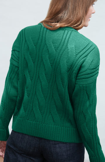 Green cable paul james wool knit sweater worn by a person on a white background