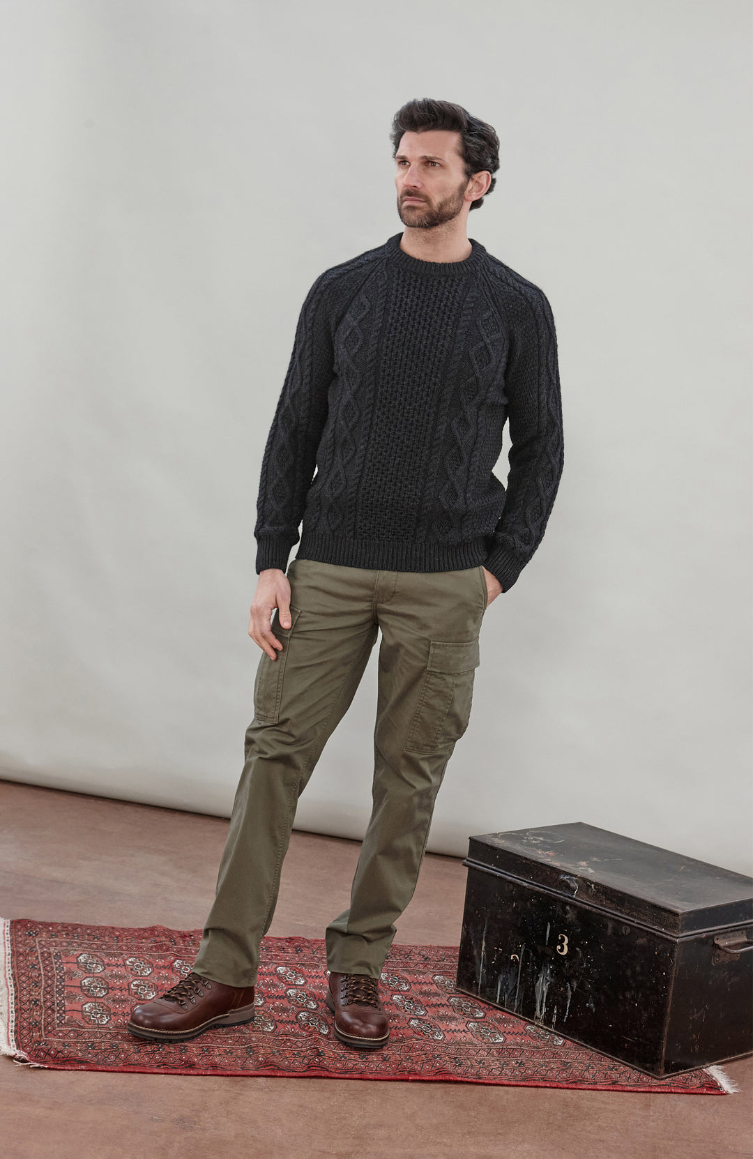Man wearing a black wool cable sweater Made in England by Paul James Knitwear