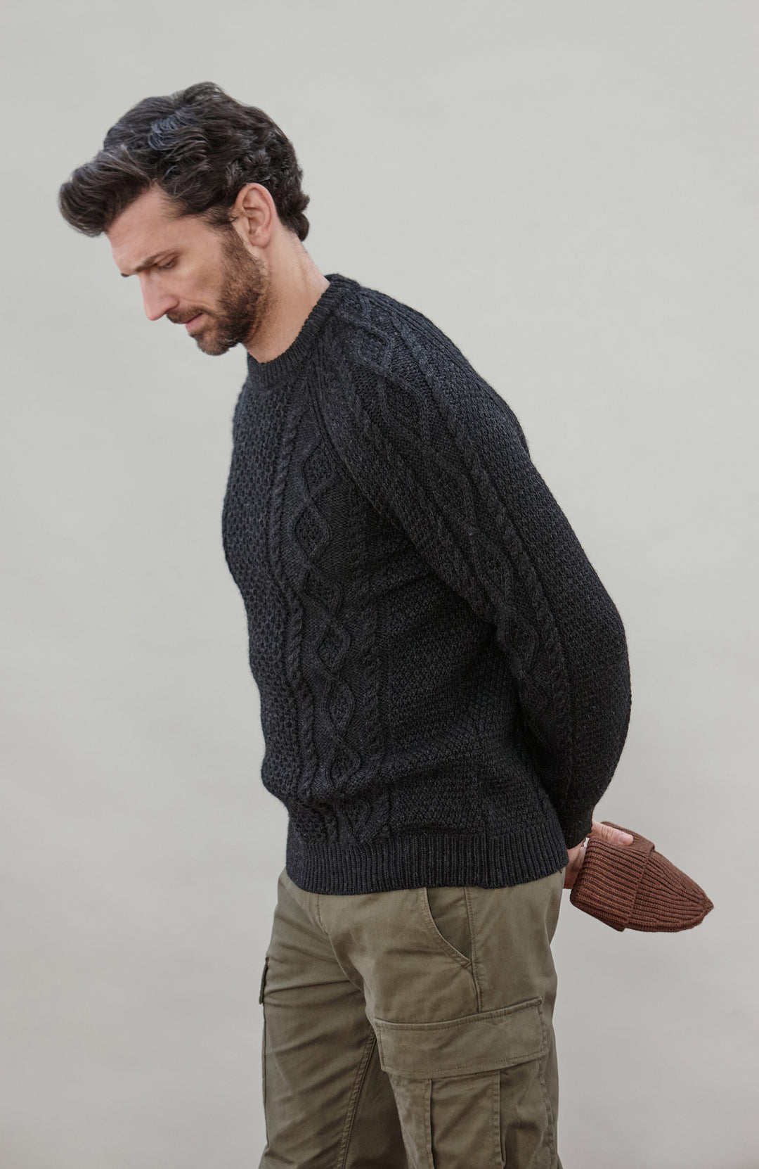 Man wearing a black wool cable sweater Made in England by Paul James Knitwear