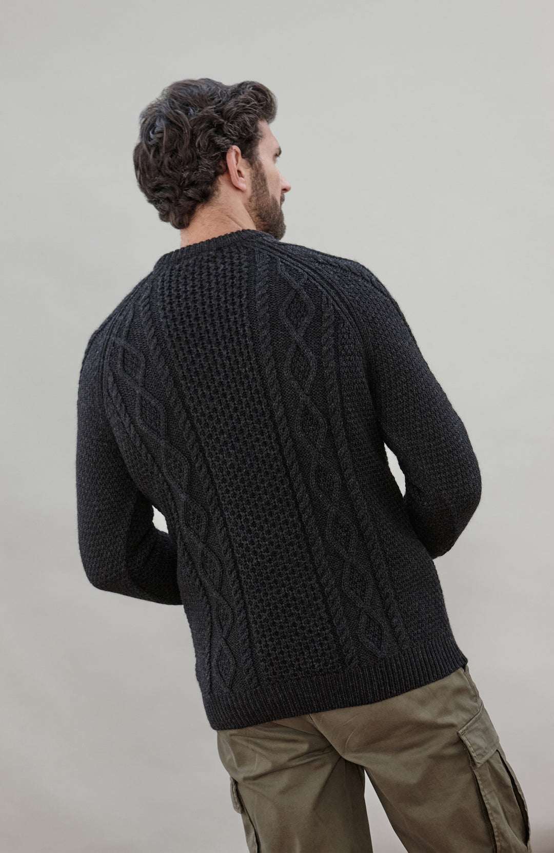Man wearing a black wool cable sweater Made in England by Paul James Knitwear