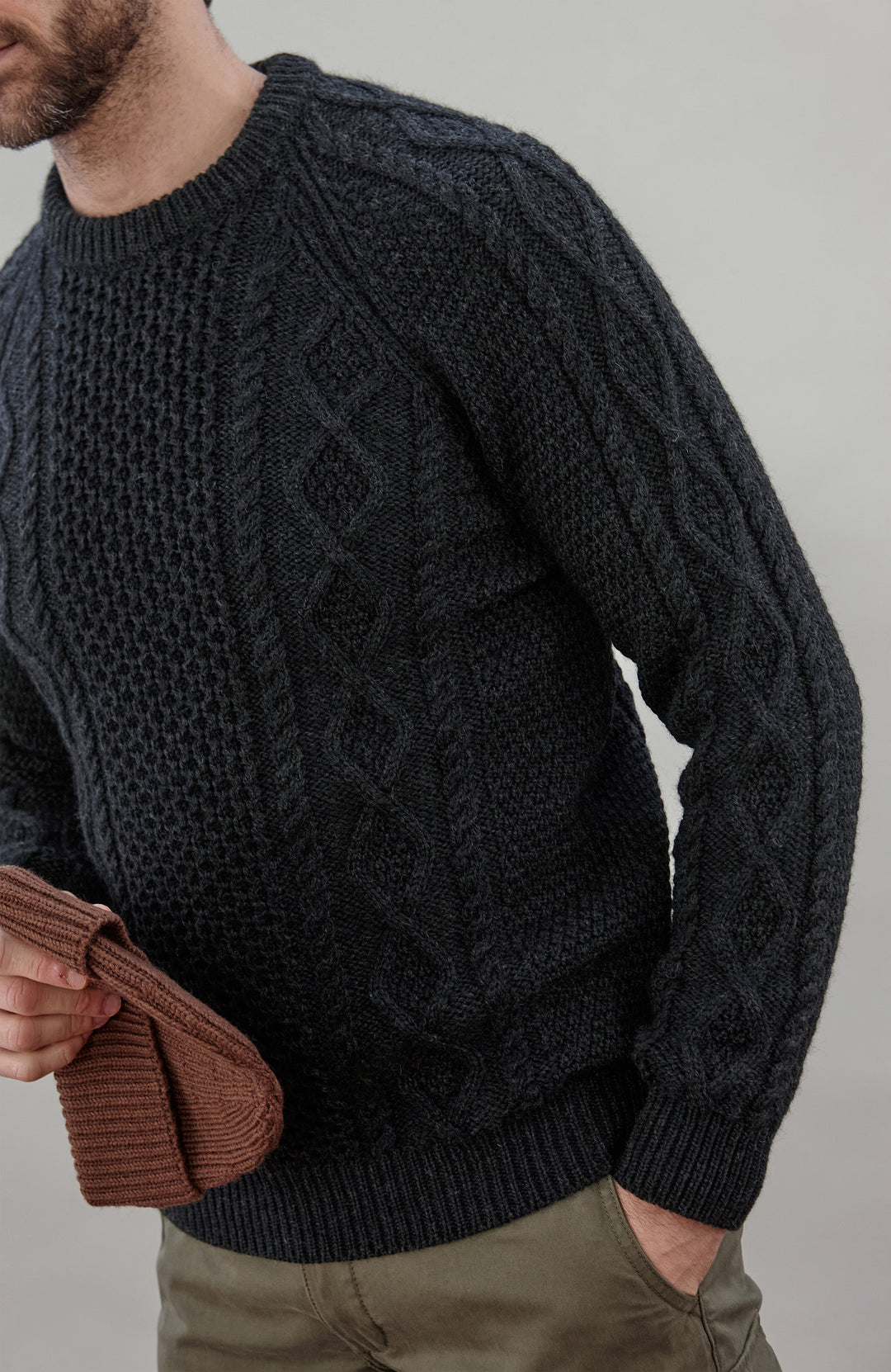Man wearing a black wool cable sweater Made in England by Paul James Knitwear