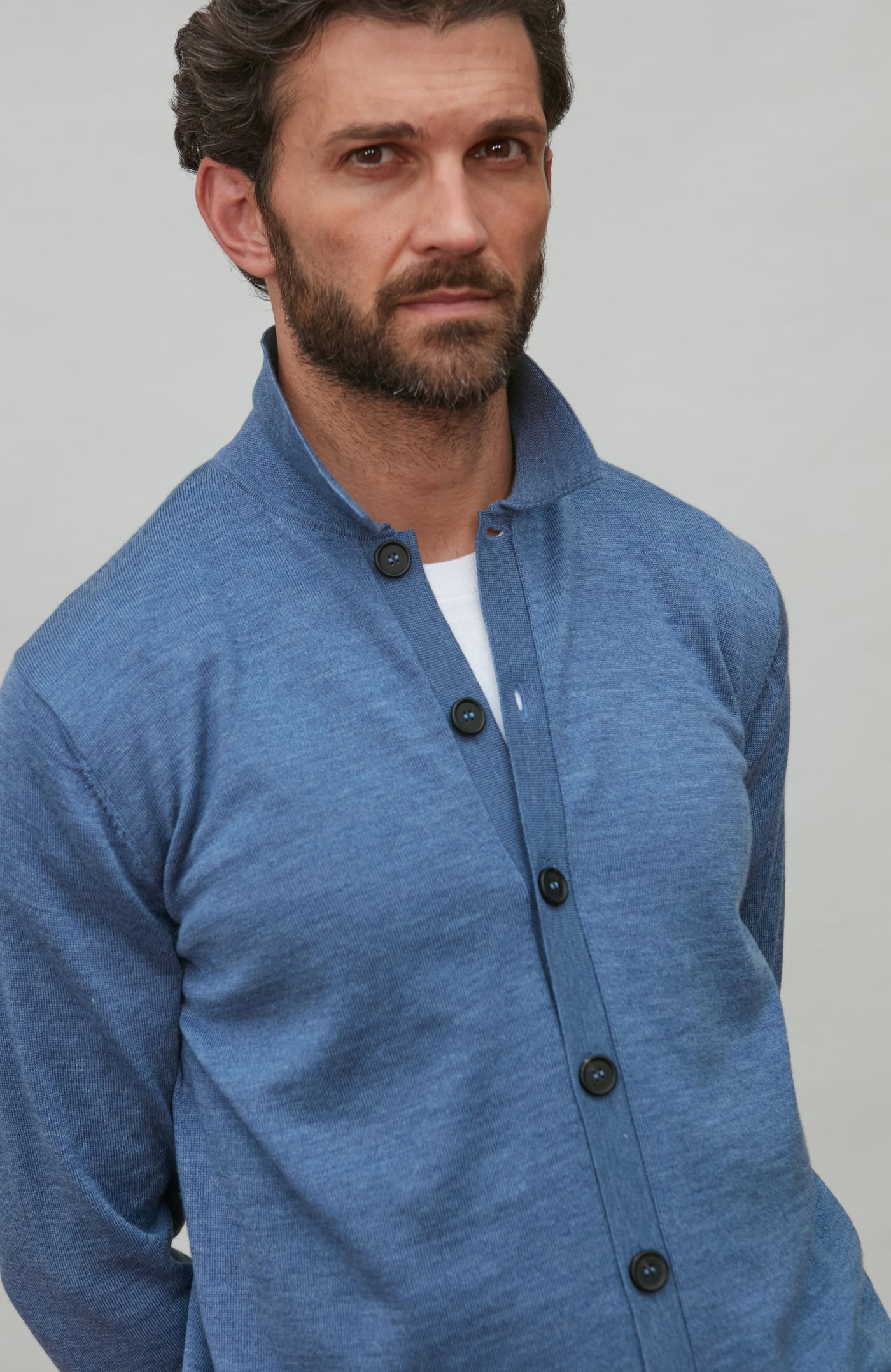 Man wearing a denim blue merino wool button-up shirt against a gray background