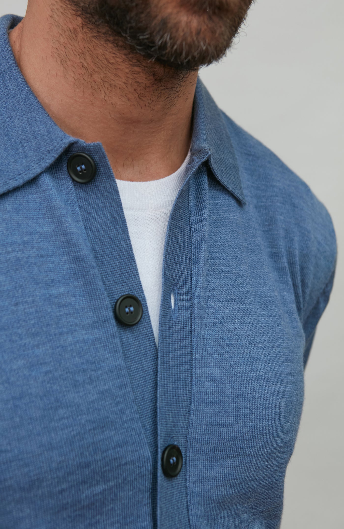 Man wearing a denim blue merino wool button-up shirt against a gray background
