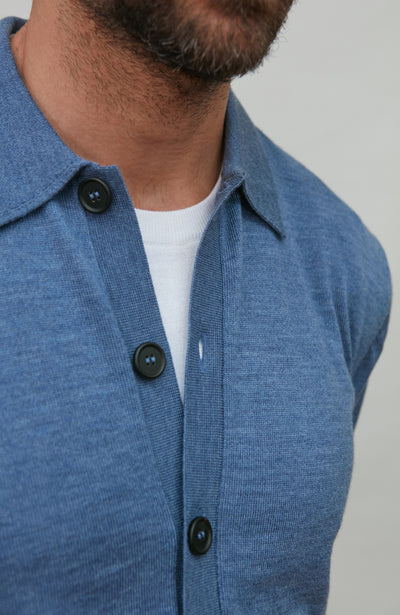 Man wearing a denim blue merino wool button-up shirt against a gray background