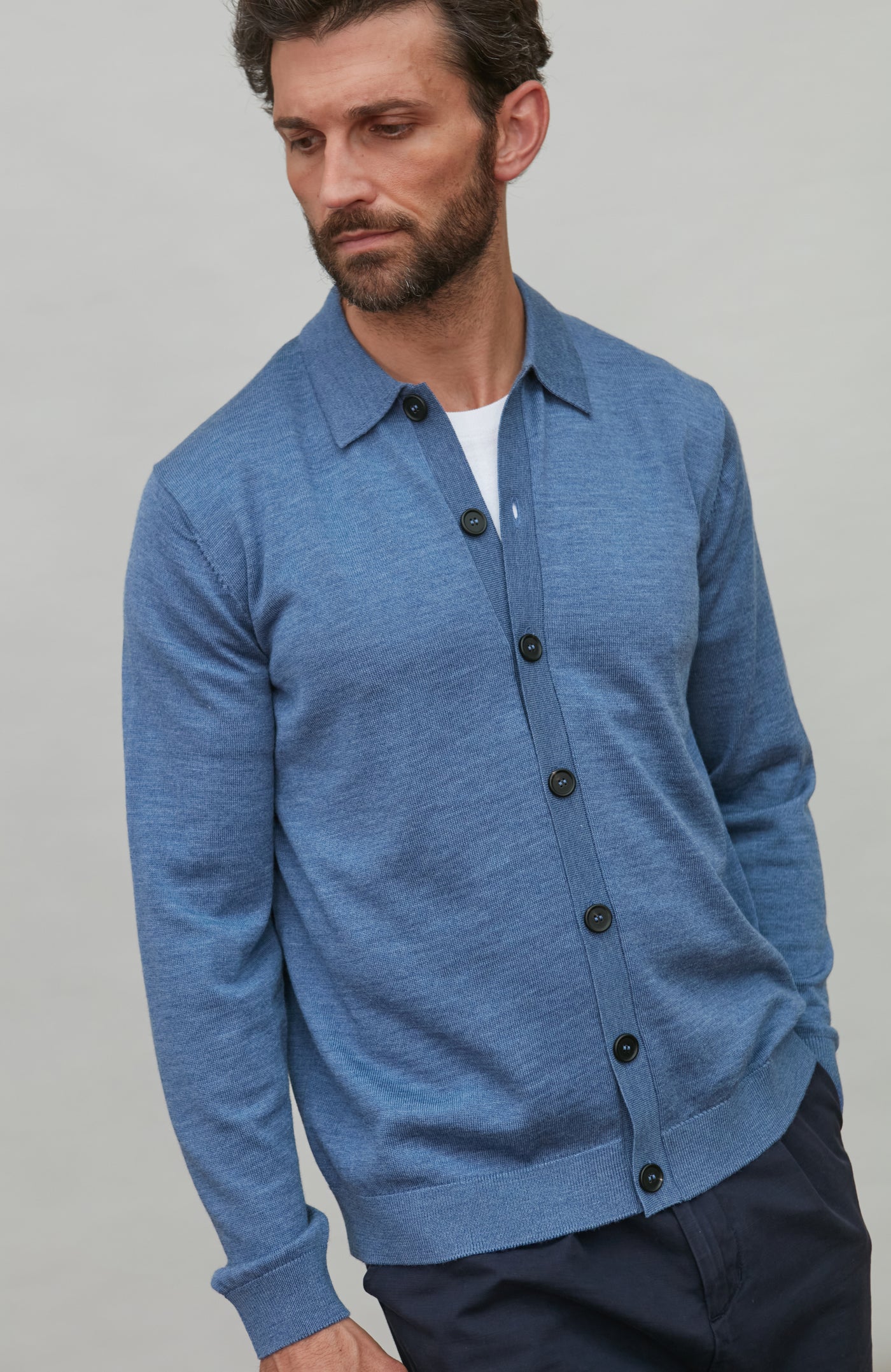 Man wearing a denim blue merino wool button-up shirt against a gray background