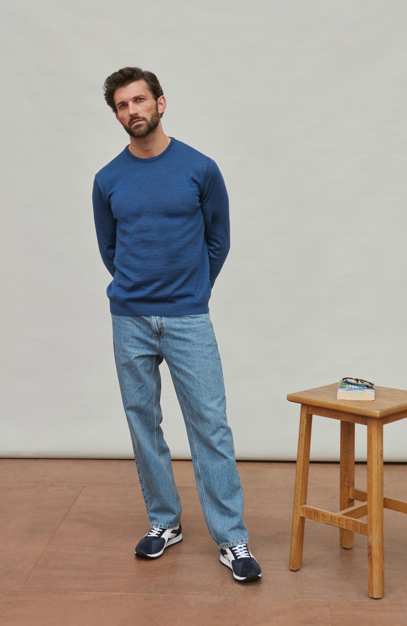 Man wearing a blue fine merino wool sweater against a gray background