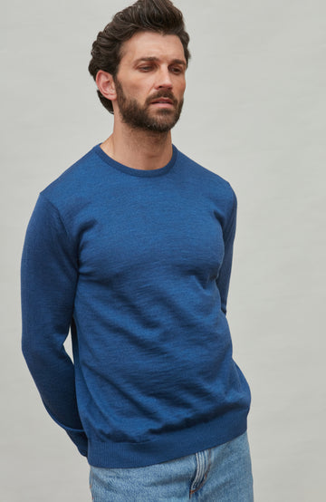 Man wearing a blue fine merino wool sweater against a gray background by Paul James