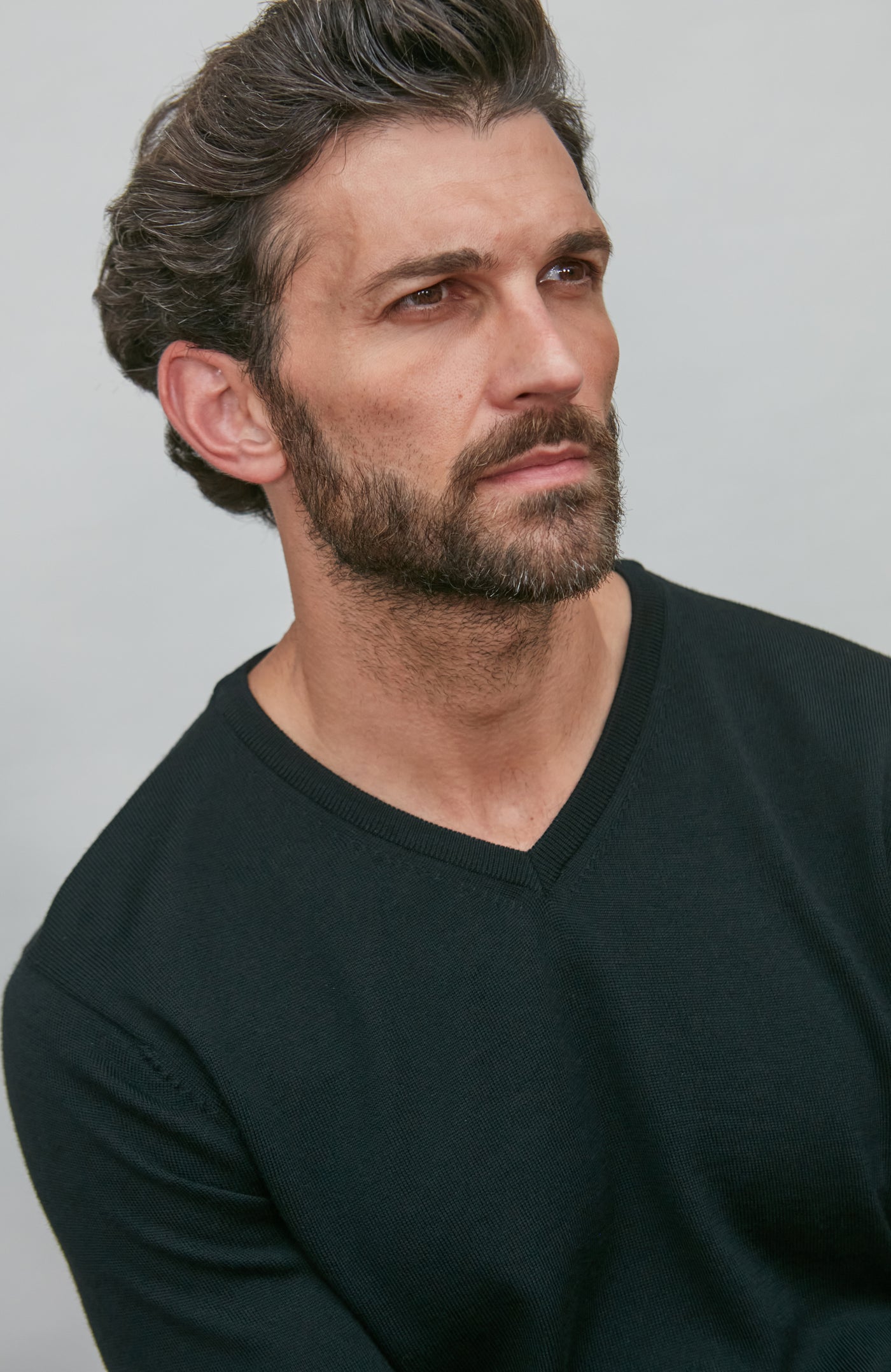 Man wearing a black v neck sweater shirt against a plain background