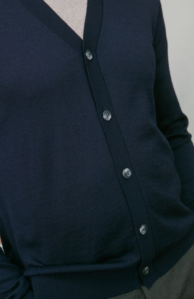 Navy blue merino wool cardigan with silver buttons on a neutral background