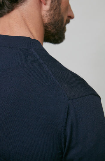 Man wearing a navy merino wool cardigan against a plain background