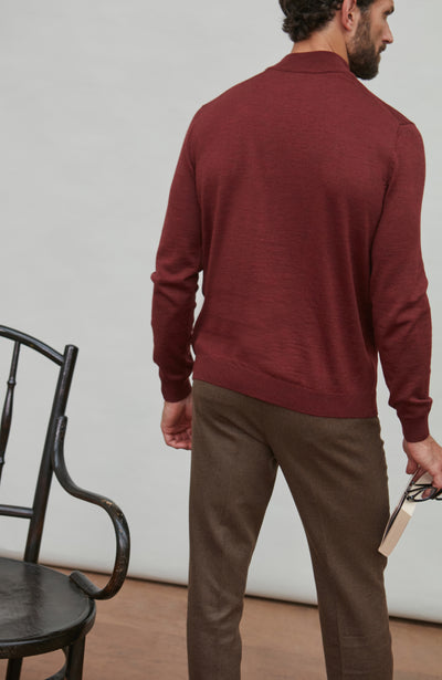 Man wearing a red merino wool mock turtleneck sweater sitting on a chair.