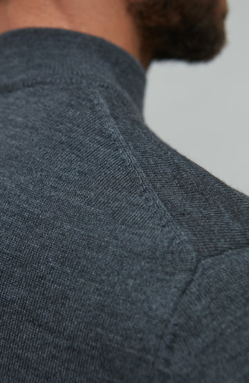 Man wearing a dark gray merino wool turtle neck sweater by Paul James