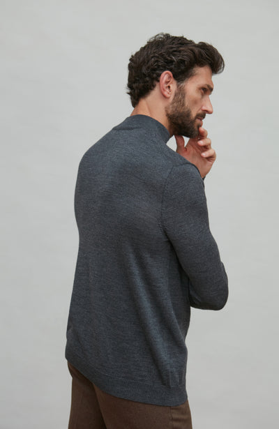 Man wearing a dark gray turtle neck sweater against a light gray background