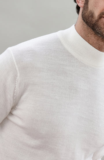 Close-up of a man wearing a cream-colored merino wool knit mock neck sweater, showing the fine knit texture and collar detail.