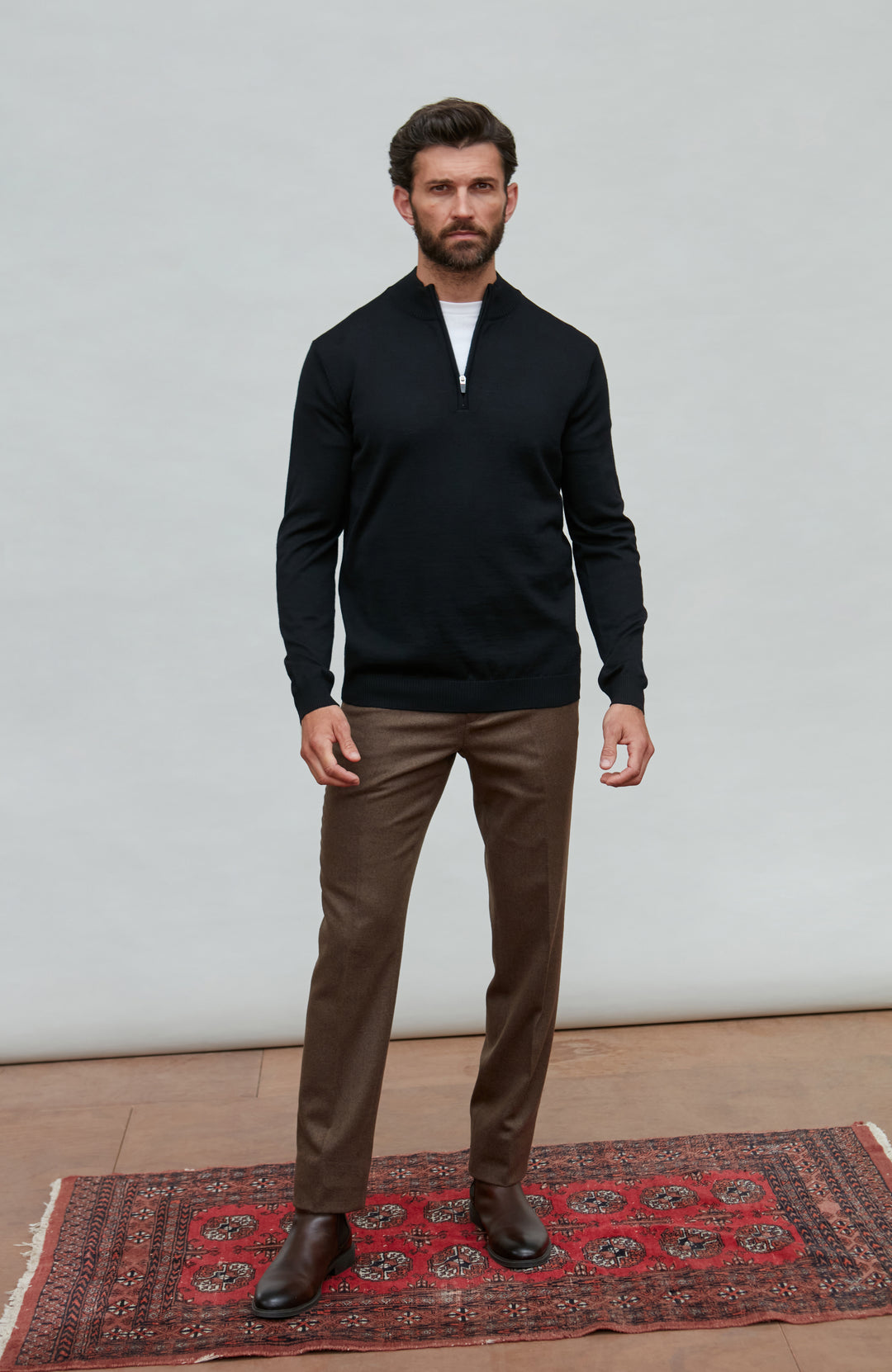 Man wearing a black quarter-zip merino wool sweater against a gray background