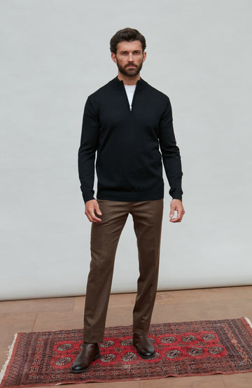Man wearing a black quarter-zip merino wool sweater against a gray background