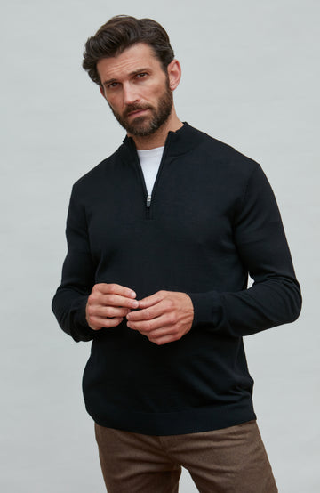 Man wearing a black quarter-zip merino wool sweater against a gray background